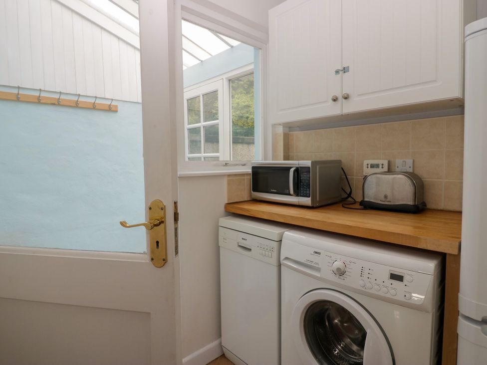 A utility room with a washing machine and a microwave at 8 Railway Cottages in Ulverston