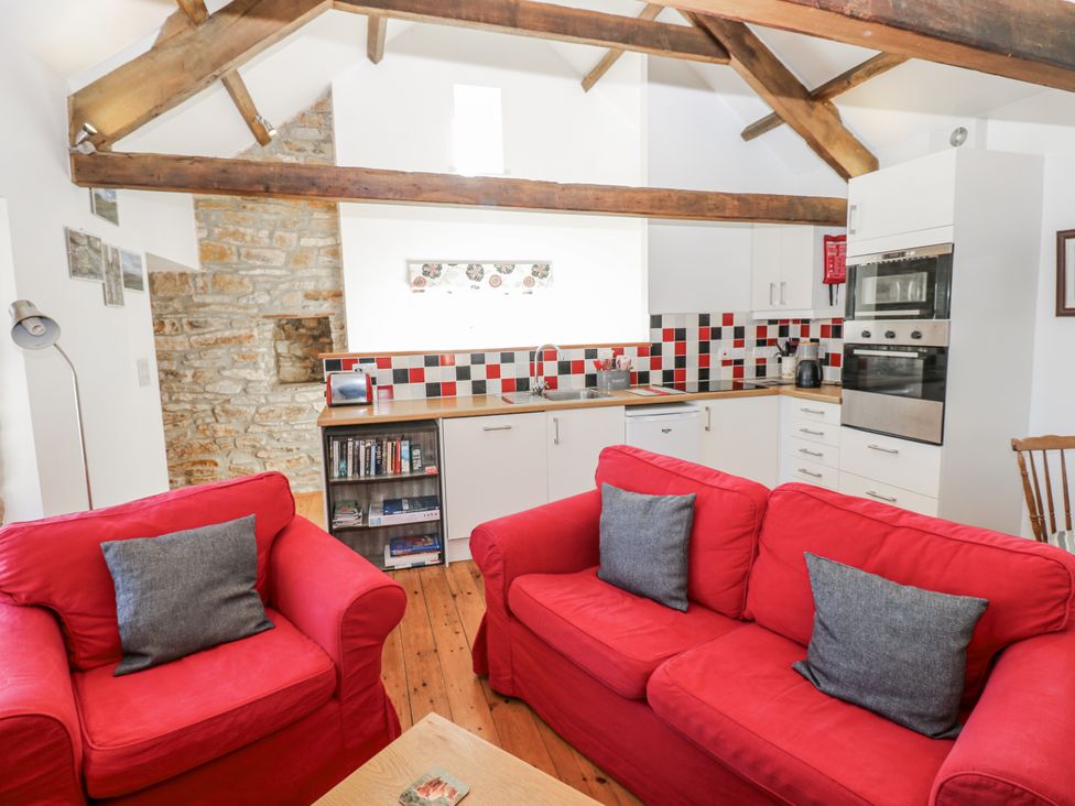 A kitchen with red sofas and a wooden table at Dove Cottage Hexham