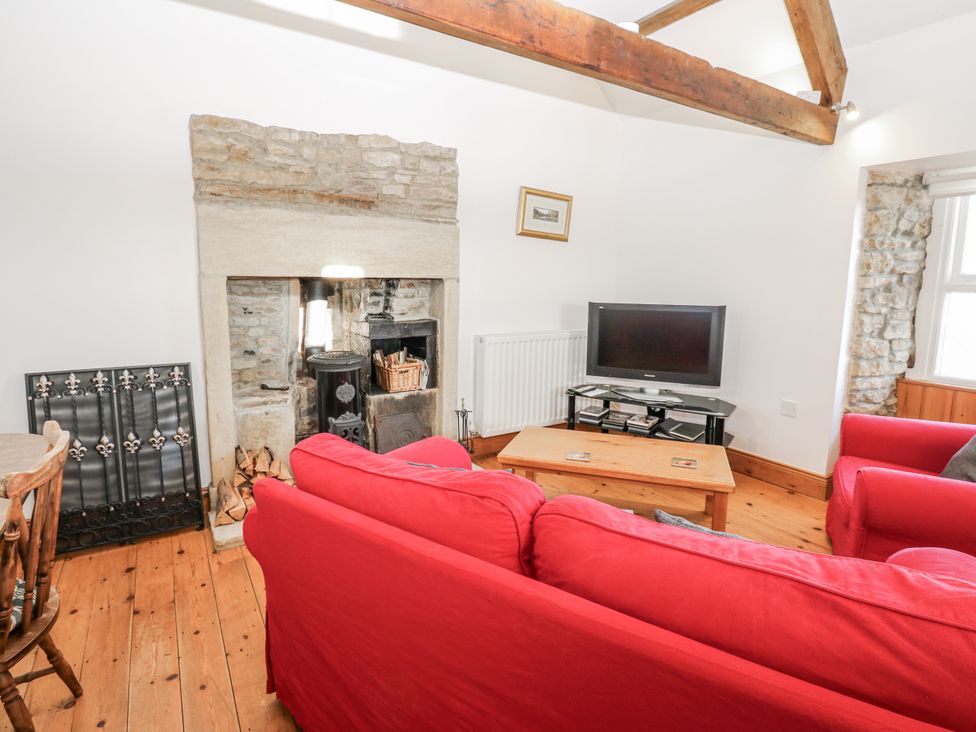 A living room with a fireplace and television at Dove Cottage in Hexham