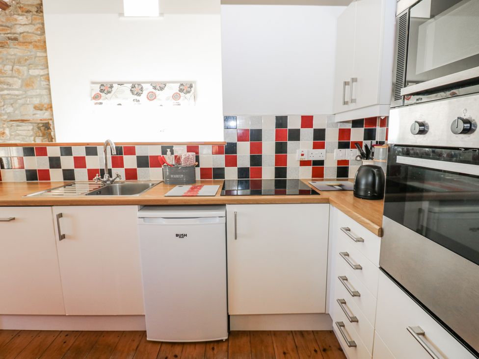 A kitchen with cabinets and appliances at Dove Cottage Hexham