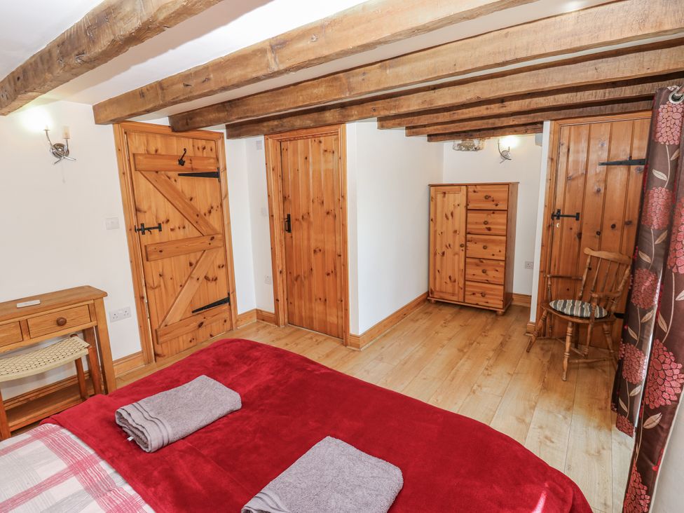 A bedroom with a bed and wooden furniture at Dove Cottage in Hexham
