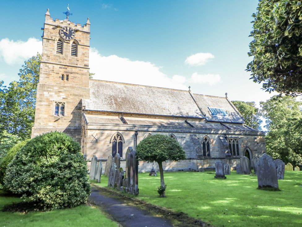 A church with a clock tower and graveyard at Dove Cottage in Hexham