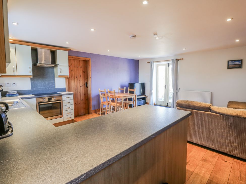 A kitchen and living room with an oven and dining table at Swallows Rest in Hexham