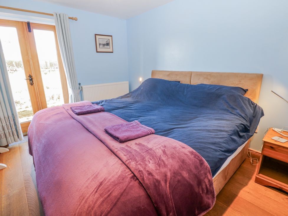 A bedroom with a large bed and a door leading outside at Swallows Rest in Hexham