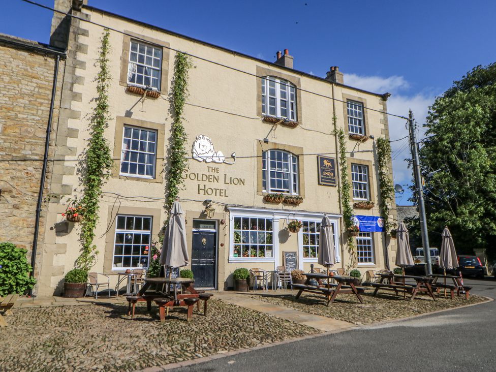 Exterior view of The Golden Lion Hotel in Hexham with tables and parasols