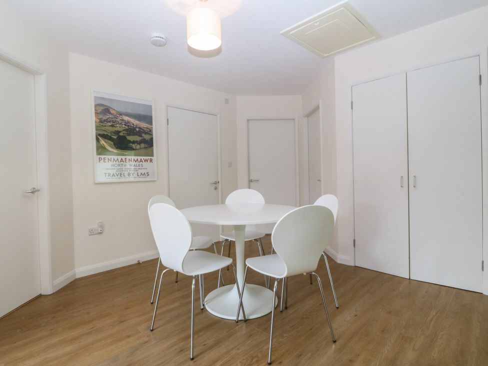 A dining room with a round table and white chairs at Orme View Penmaenmawr