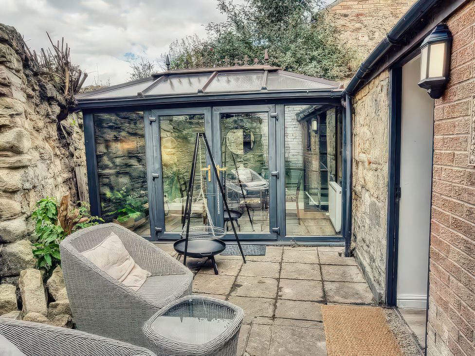 A conservatory with glass doors and seating area at 20 Bridge Street in Morpeth
