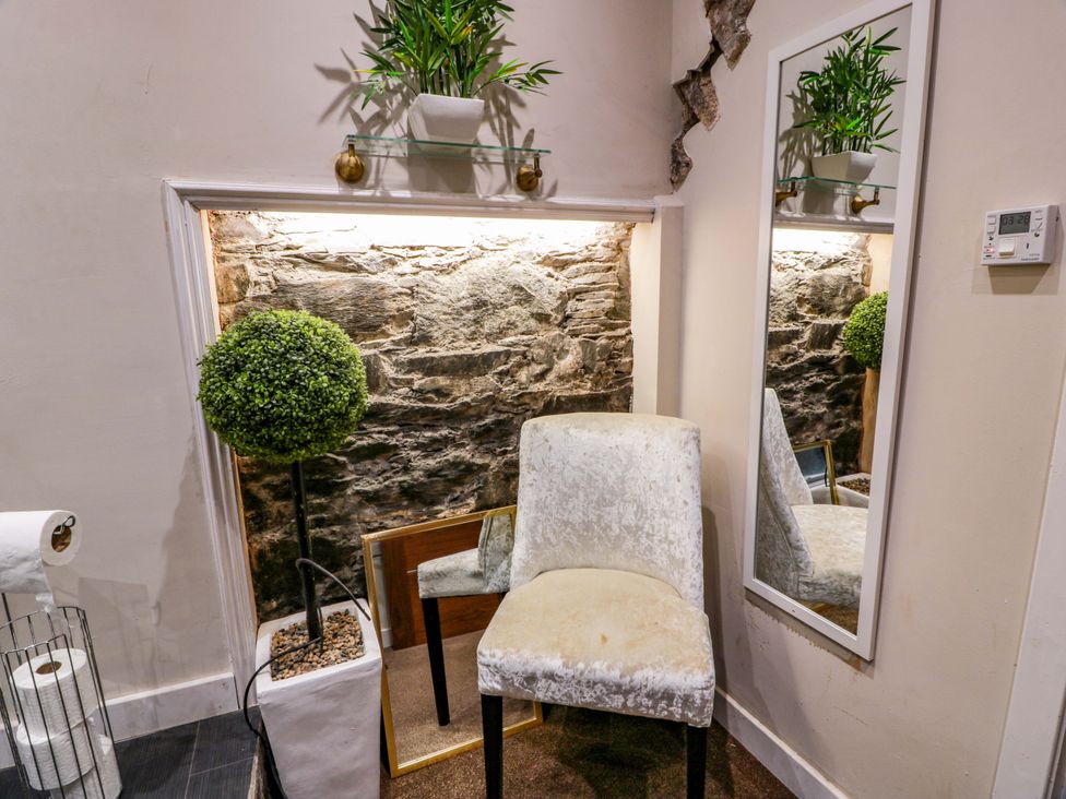 A chair and mirror with plants in a bathroom at 69 High Street in Gatehouse Of Fleet