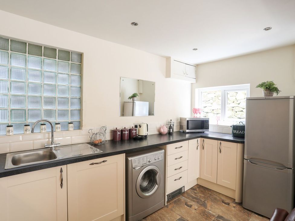A kitchen with a washing machine and refrigerator at Llys Elen in Caernarfon