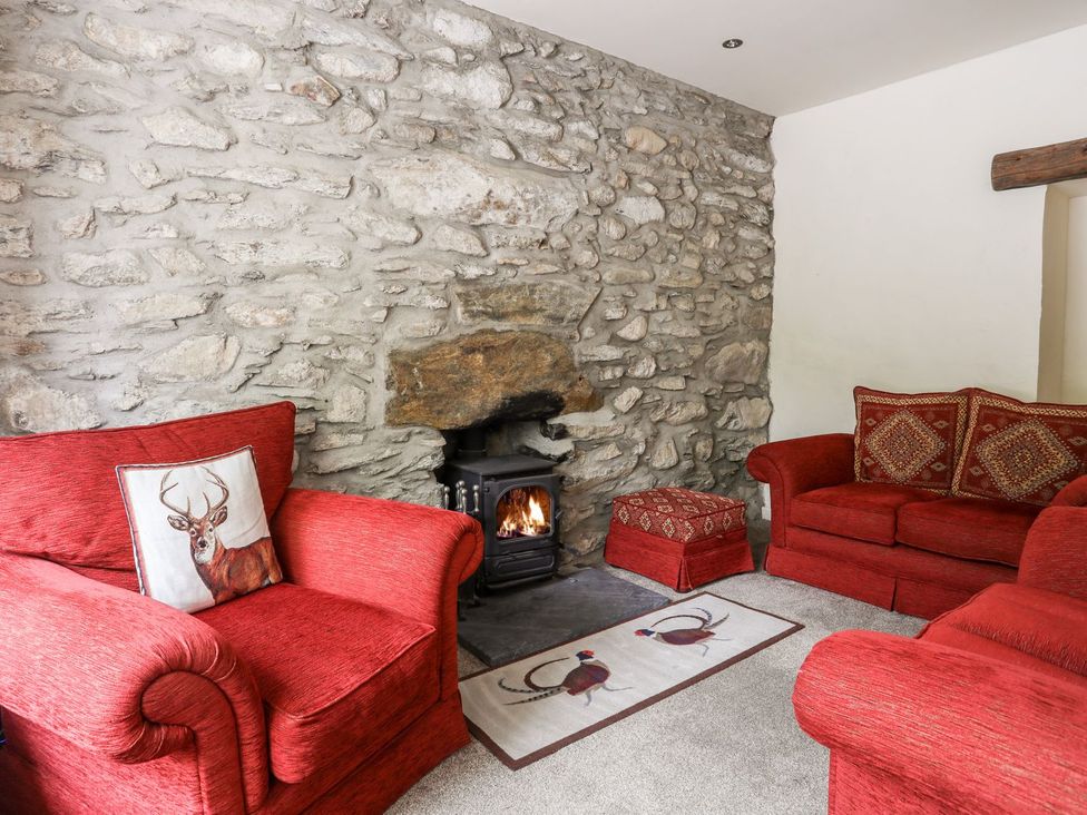 A living room with a fireplace and red sofas at Llys Elen in Caernarfon