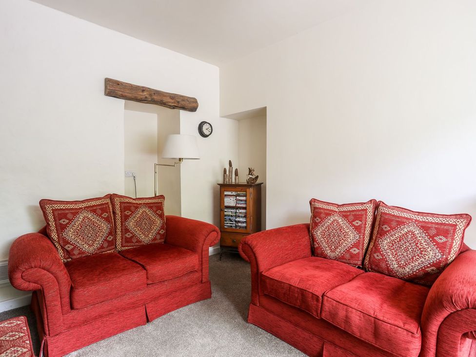A living room with red sofas and a cabinet at Llys Elen in Caernarfon