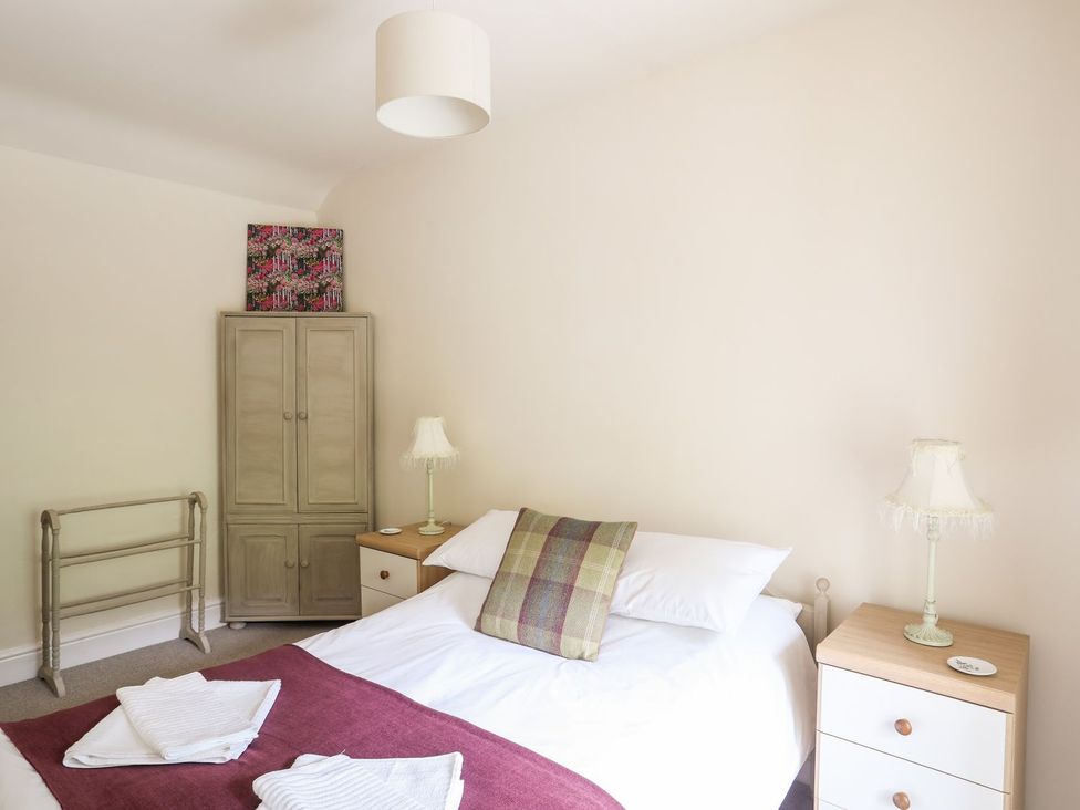 A bedroom with a bed, wardrobe, and bedside table at Llys Elen in Caernarfon