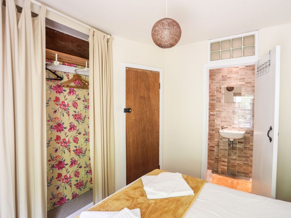 A bedroom with a bed, wardrobe, and bathroom at Llys Elen in Caernarfon