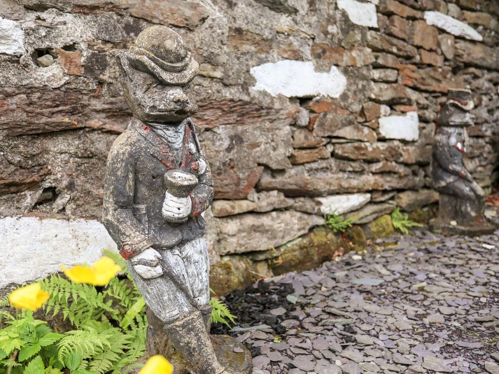A garden with a stone wall and a statue at Llys Elen Caernarfon