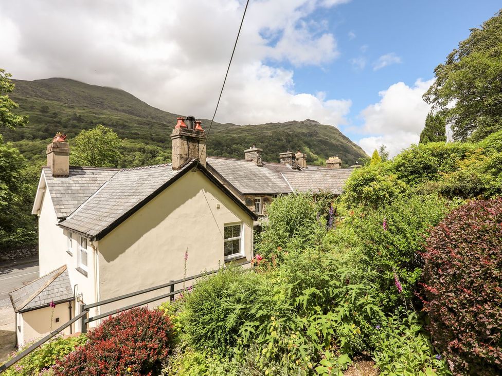 A house with a garden and mountains in the background at Llys Elen in Caernarfon