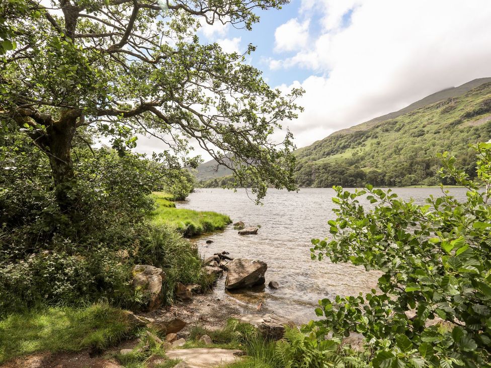 A scenic view of a lake with trees and rocks at Llys Elen in Caernarfon