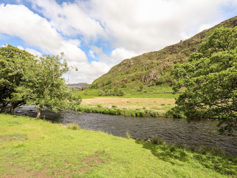 A river with grass and trees beside it at Llys Elen in Caernarfon