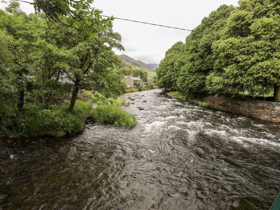 A river surrounded by trees and houses at Llys Elen in Caernarfon