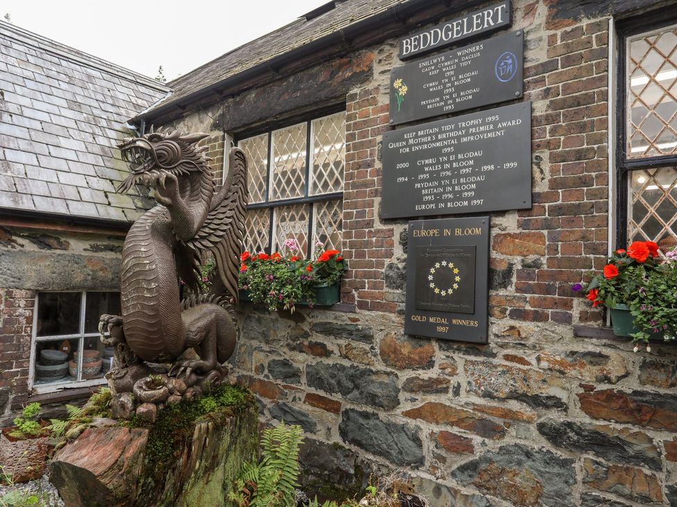 A dragon statue and plaques on a brick wall in Beddgelert, Caernarfon