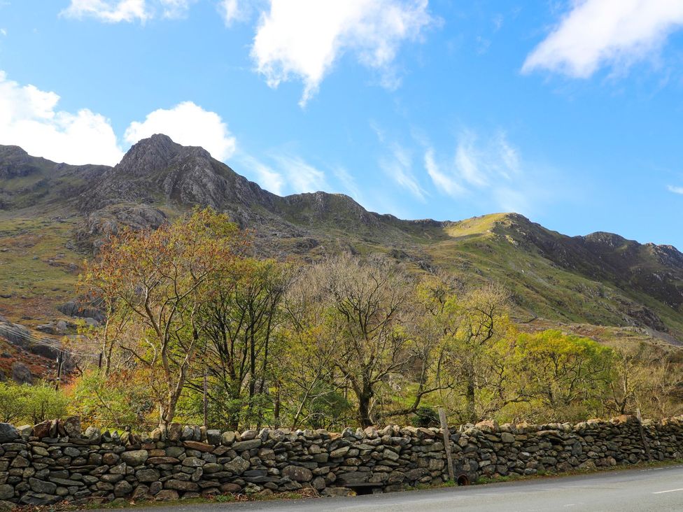 Mountains and trees beside a stone wall along a road at Llys Elen in Caernarfon