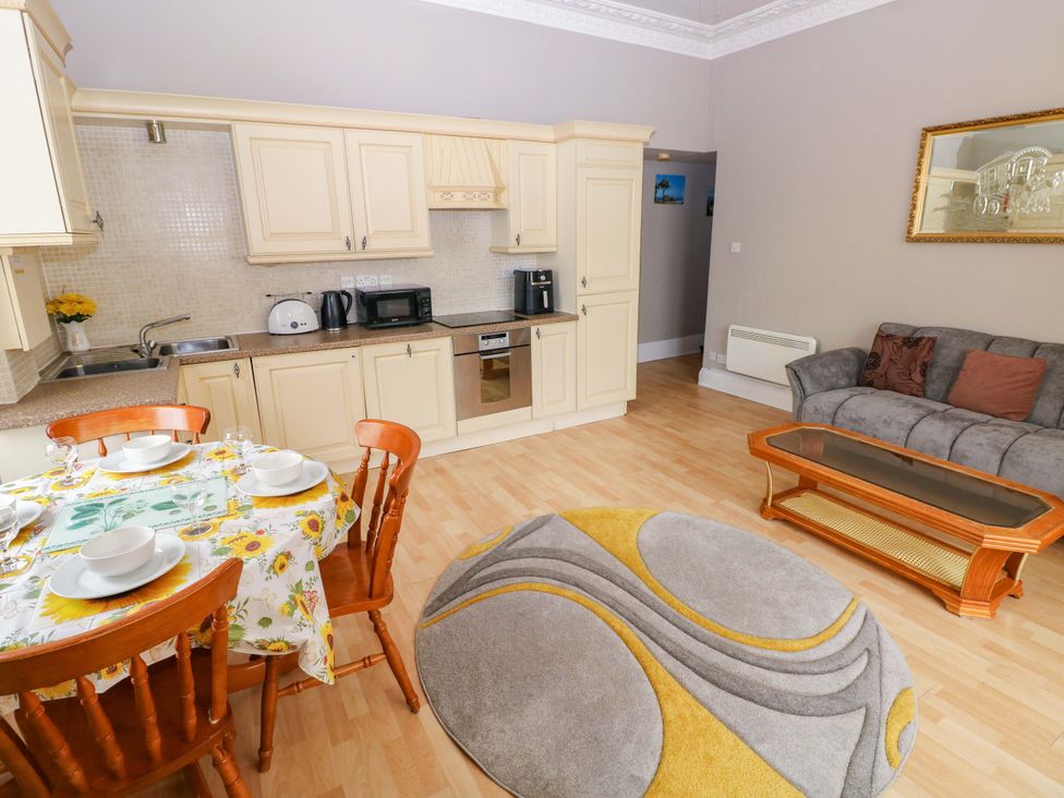 A living room with a kitchen area and dining table at 1 Hilton Flats Tenby