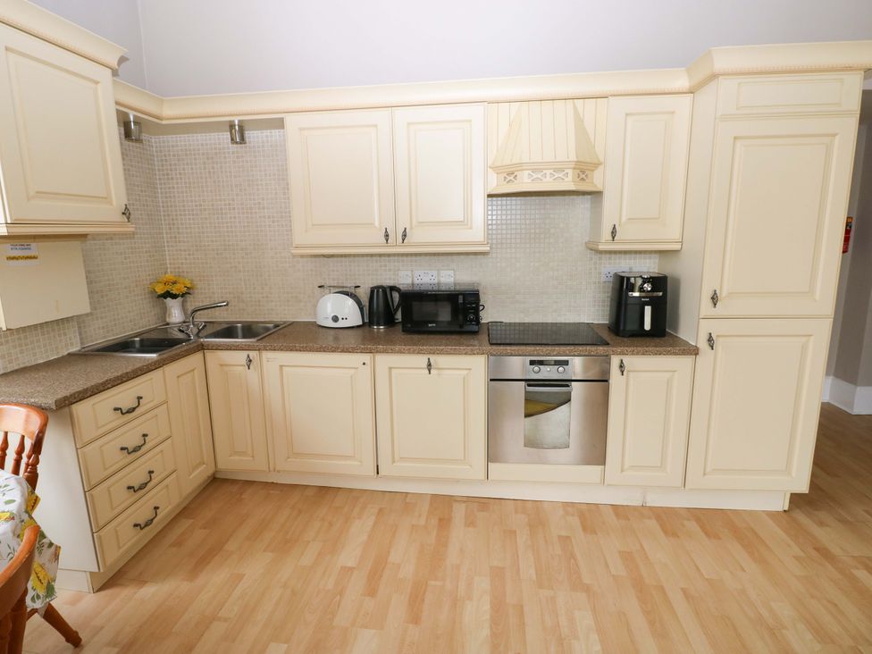 A kitchen with sink, cabinets, and appliances at 1 Hilton Flats Tenby
