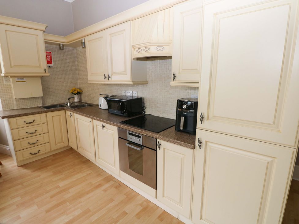 A kitchen with cabinets and appliances at 1 Hilton Flats Tenby