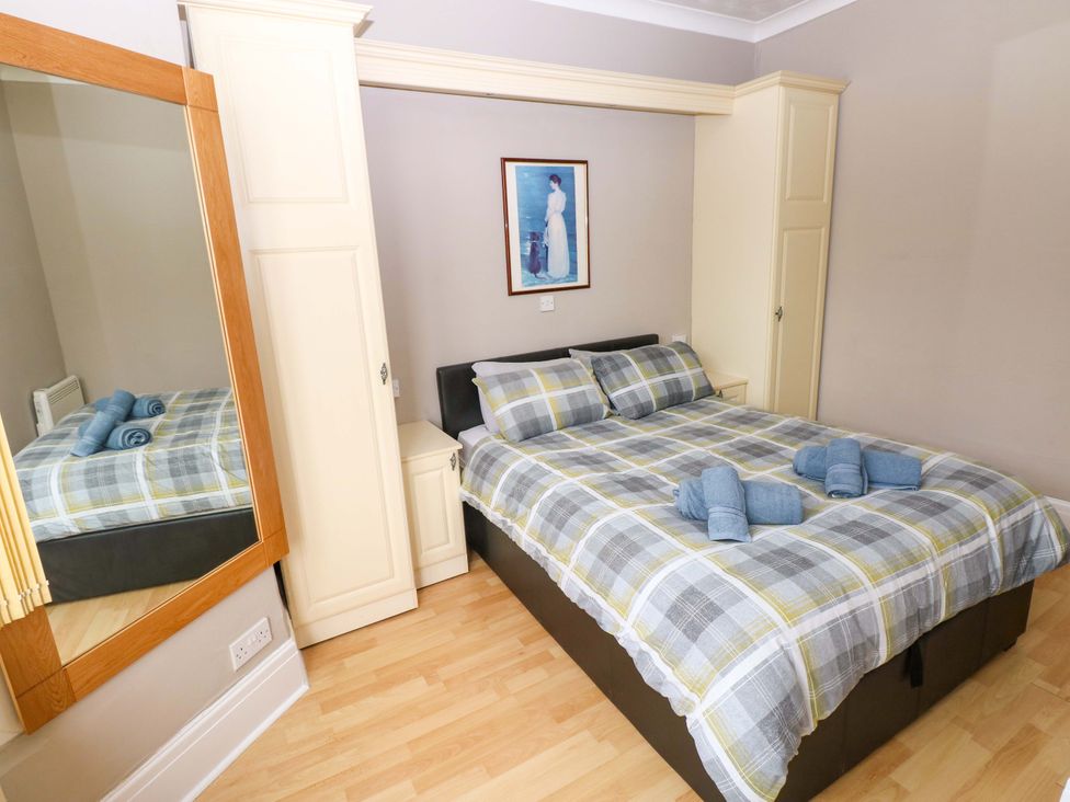 A bedroom with a bed and mirror at 1 Hilton Flats in Tenby