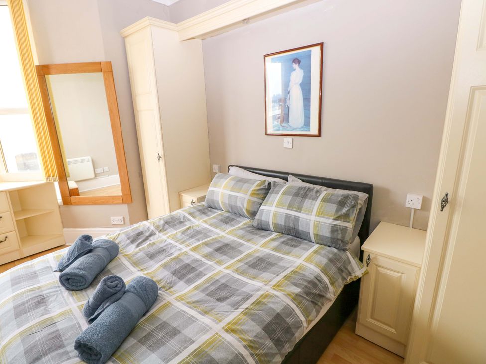 A bedroom with a bed and towels at 1 Hilton Flats in Tenby