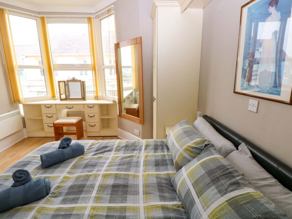 A bedroom with a bed and dressing table at 1 Hilton Flats in Tenby