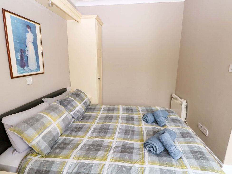 A bedroom with a bed and wall art at 1 Hilton Flats in Tenby