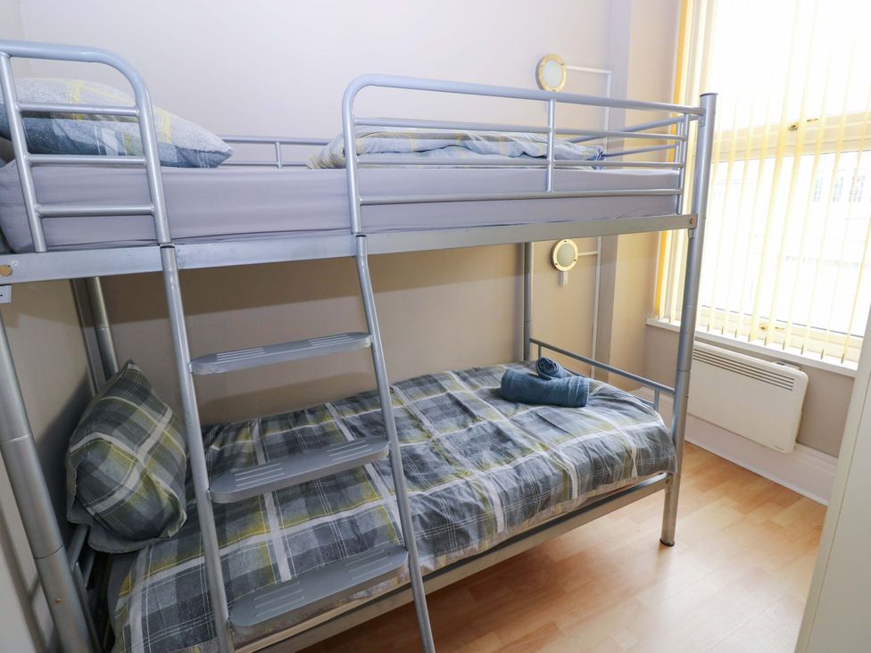 A bedroom with a bunk bed and a towel on the lower bunk at 1 Hilton Flats in Tenby