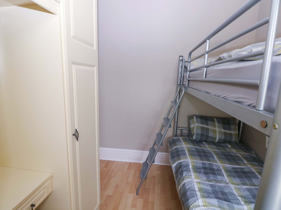 A bedroom with a bunk bed and a wardrobe at 1 Hilton Flats in Tenby