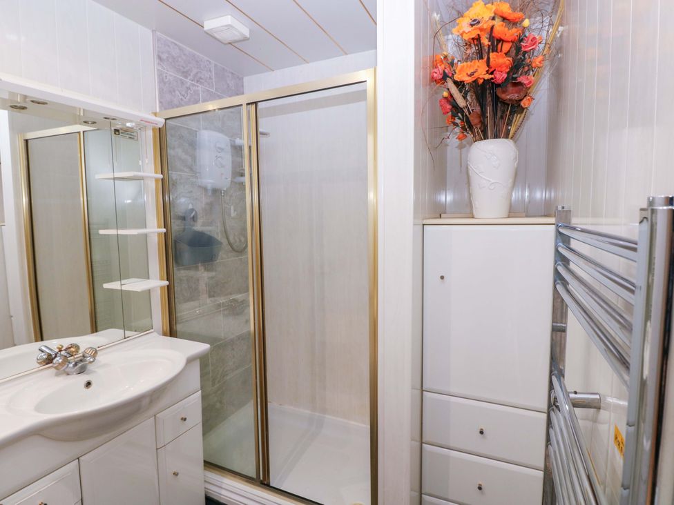 A bathroom with a shower and sink at 1 Hilton Flats in Tenby