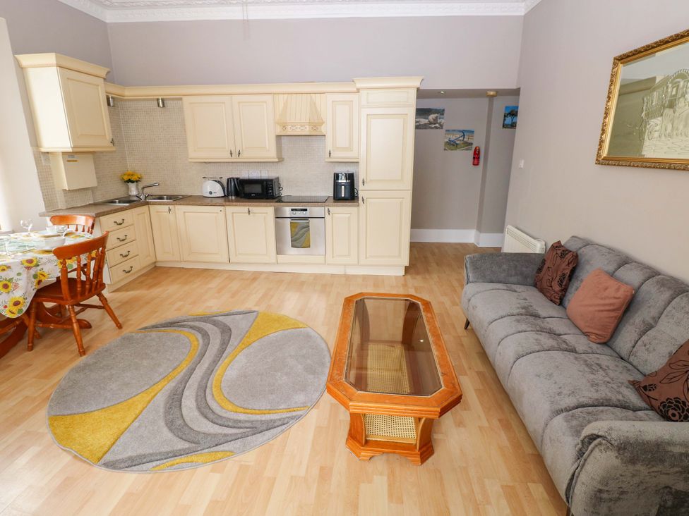 A kitchen area with a sofa and dining table at 1 Hilton Flats in Tenby