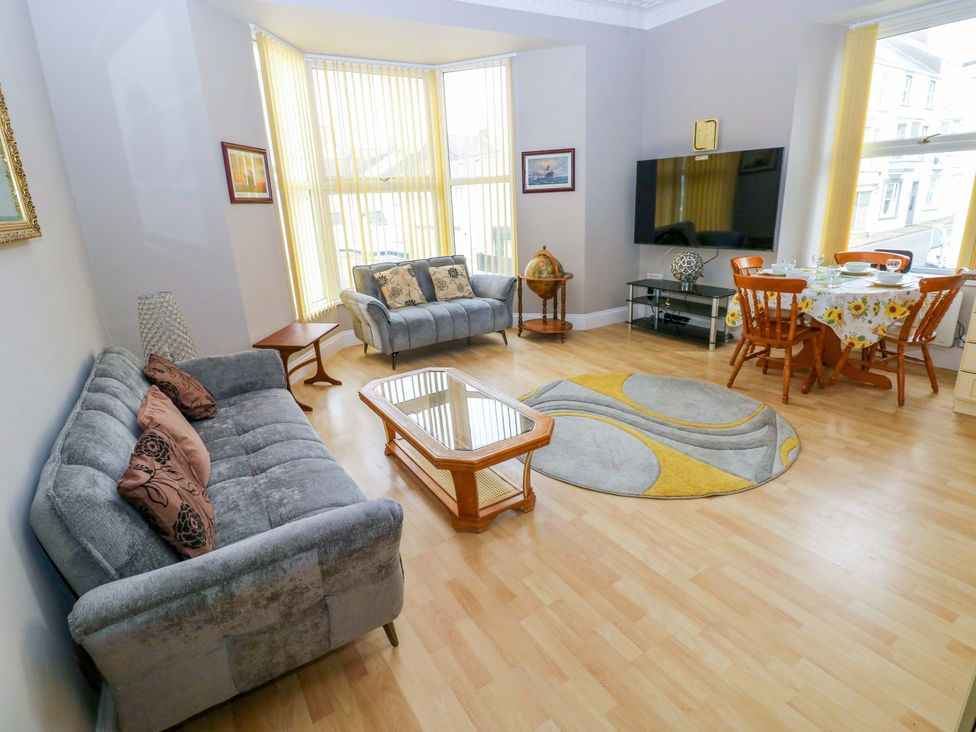A living room with a sofa and dining area at 1 Hilton Flats in Tenby