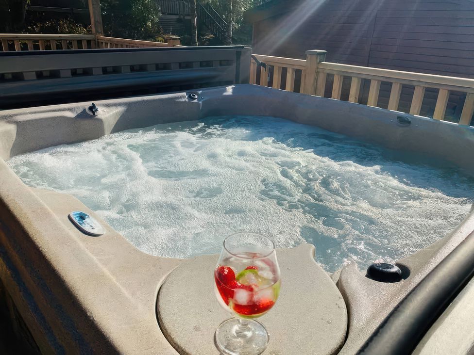 A hot tub with water and a glass of drink at Owls House - White Cross Bay in Windermere