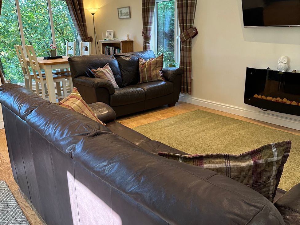 A living room with a sofa and dining area at Owls House - White Cross Bay, Windermere