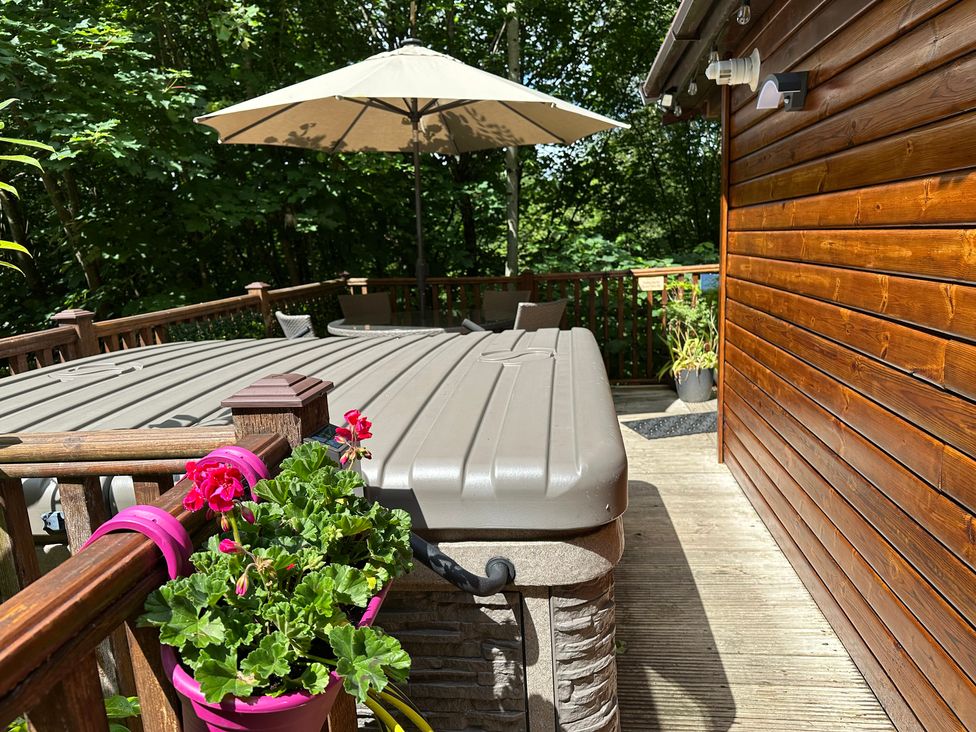 An outdoor area with a hot tub and a wooden deck at Owls House - White Cross Bay Windermere