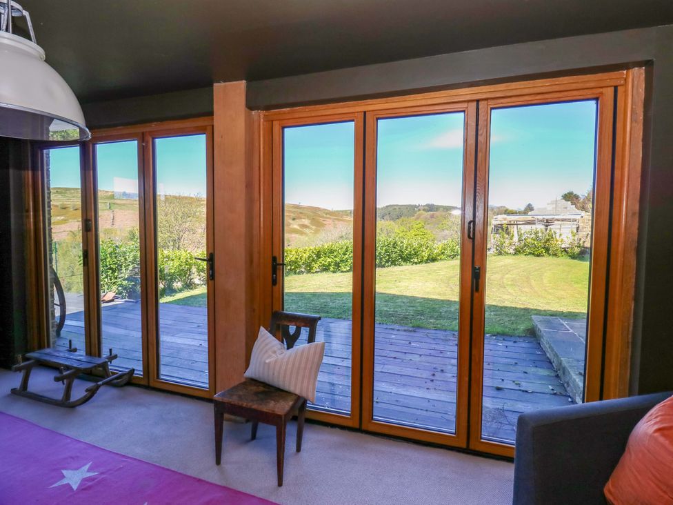 A living room with large windows overlooking a garden at Rocks Cottage Halifax