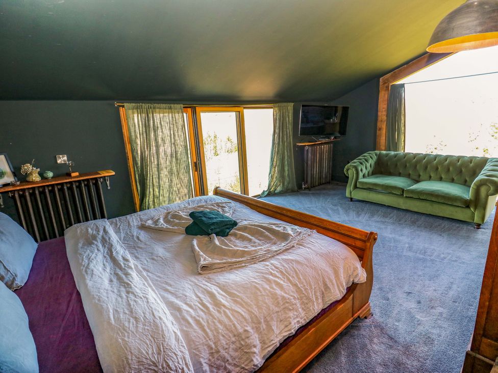 A bedroom with a bed and a green sofa at Rocks Cottage in Halifax