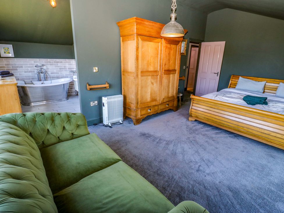 A bedroom with a bed, wardrobe, and couch at Rocks Cottage Halifax