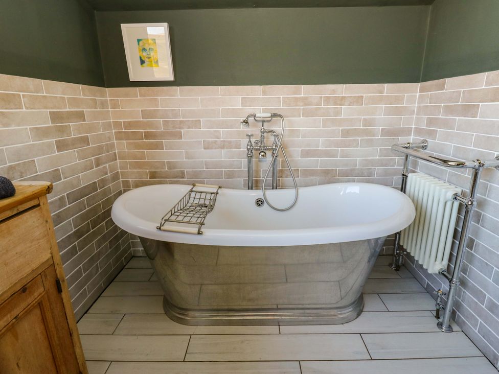 A bathroom featuring a bathtub, radiator, and wall tiles at Rocks Cottage in Halifax