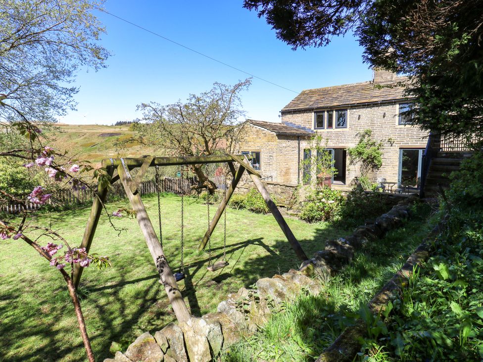 A garden with a swing set and a house at Rocks Cottage in Halifax