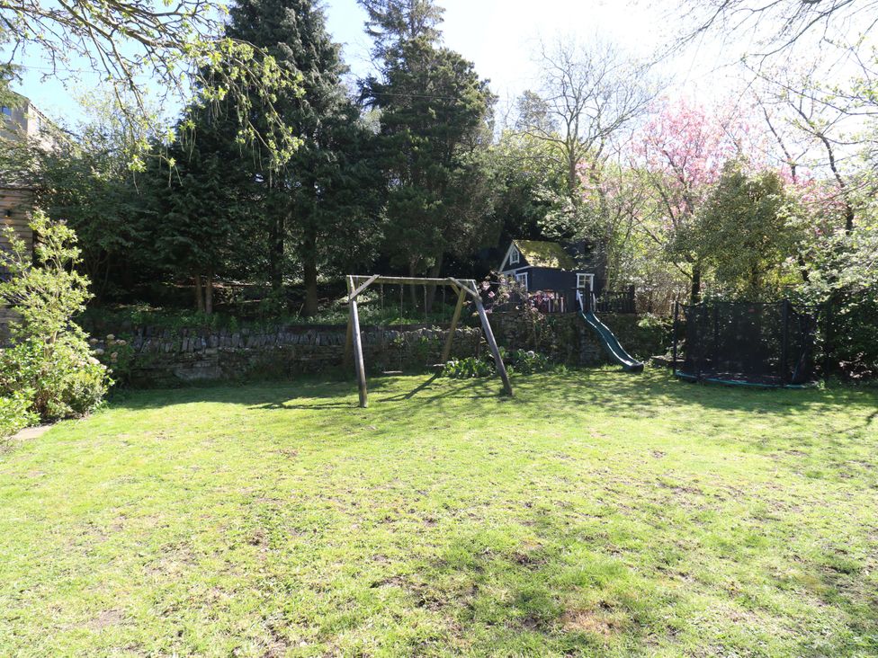 A garden with a swing set, slide, and trampoline at Rocks Cottage Halifax