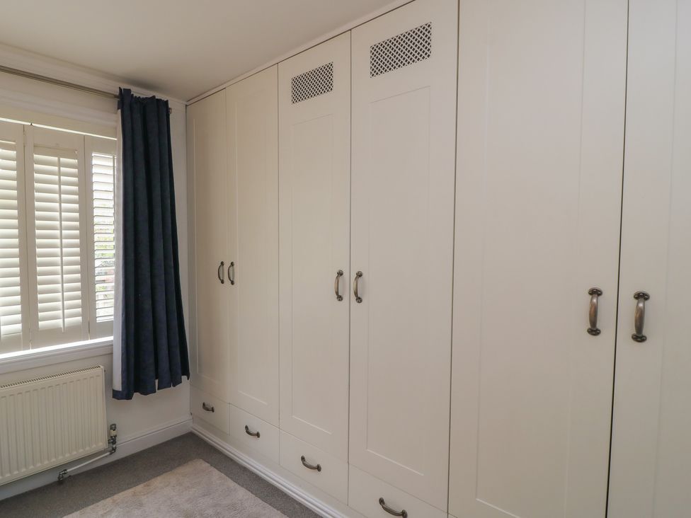 A bedroom with a wardrobe and window at Bosun's Deck in Christchurch