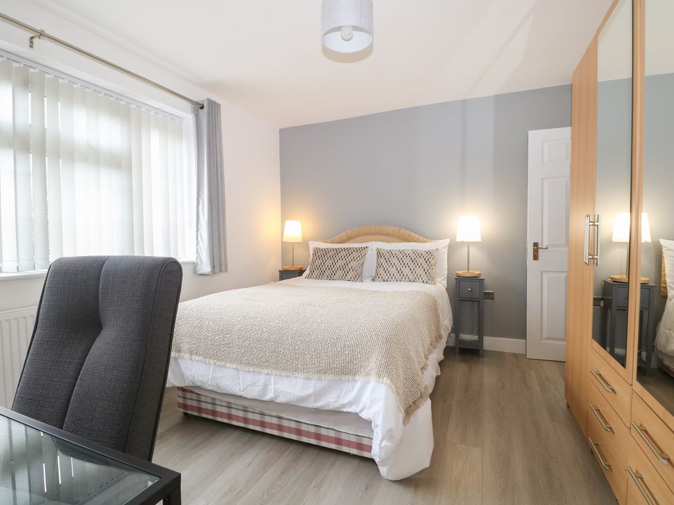 A bedroom with a bed, chair, and side tables at The Annex in Slough