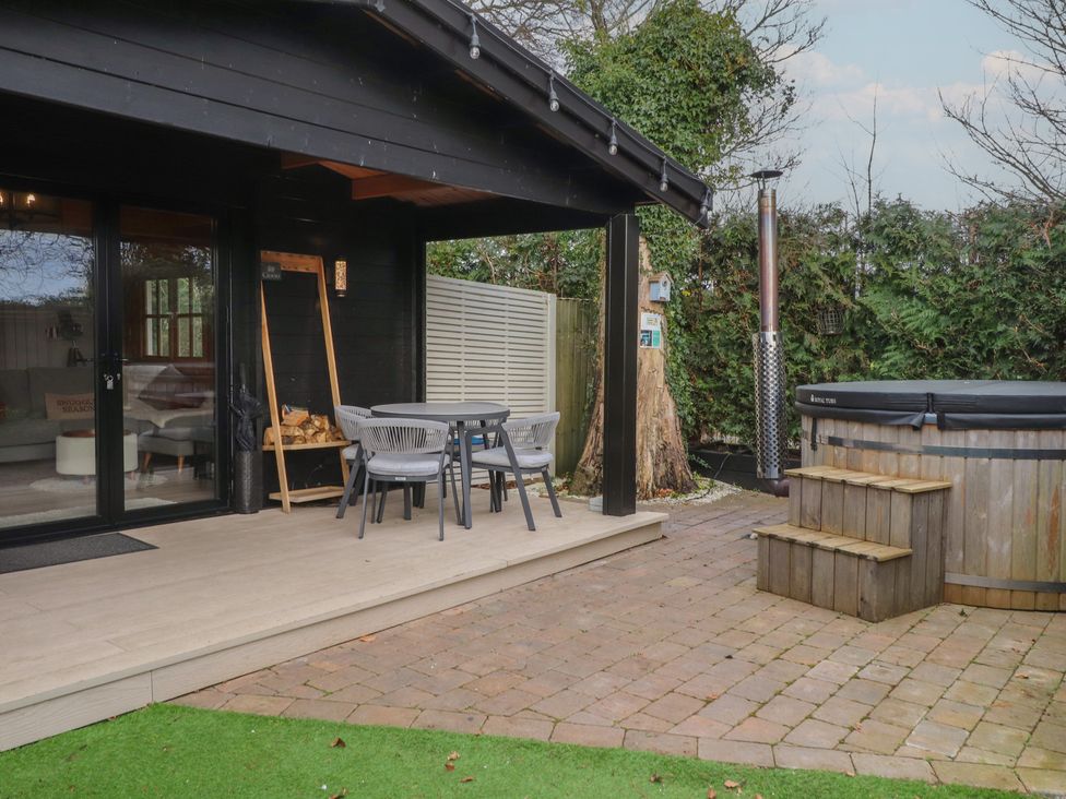 An outdoor seating area with a hot tub at Caban Tan Y Dderwen in Chwilog