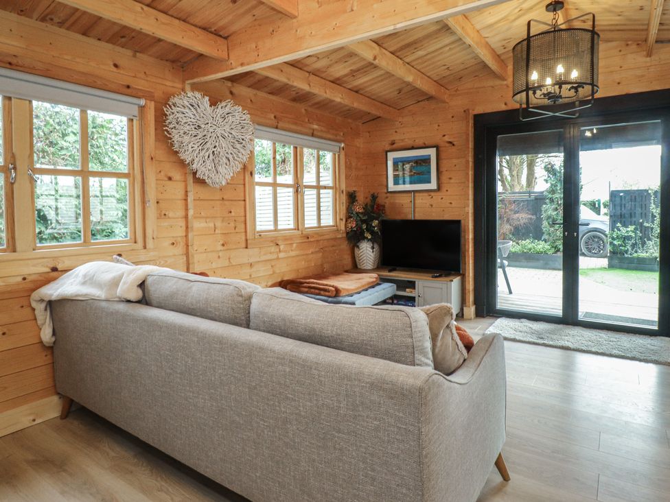 A snug with a sofa, television, and sliding doors at Caban Tan Y Dderwen in Chwilog