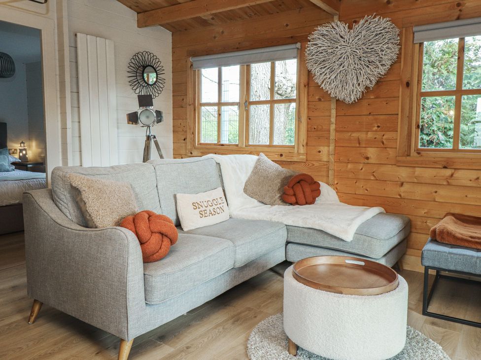 A living room with a sofa and coffee table at Caban Tan Y Dderwen in Chwilog